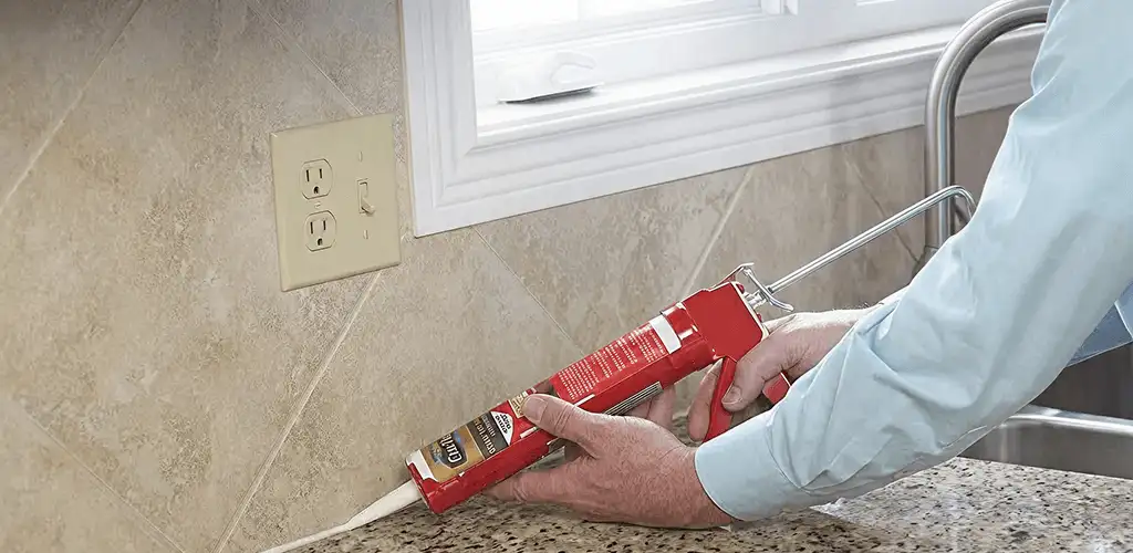 Handyman applying caulk along a kitchen backsplash and countertop seam in Buffalo, NY