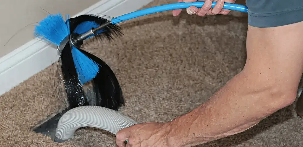 Dryer vent cleaning technician brushing lint from a vent line in Buffalo, NY