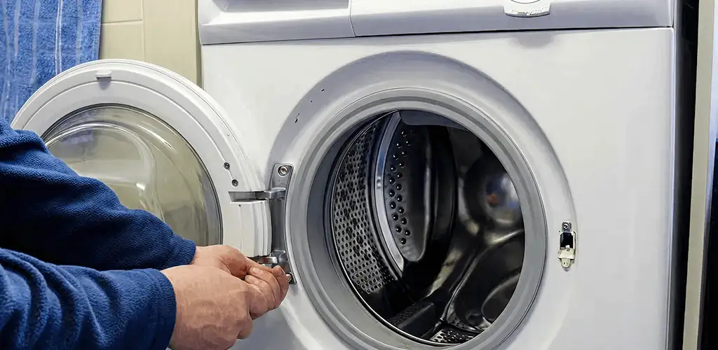 Washing machine repair handyman checking a front-load washer door and latch in Buffalo, NY