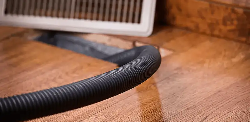 Air duct cleaning hose inserted into a floor vent for ductwork cleaning in Buffalo, NY