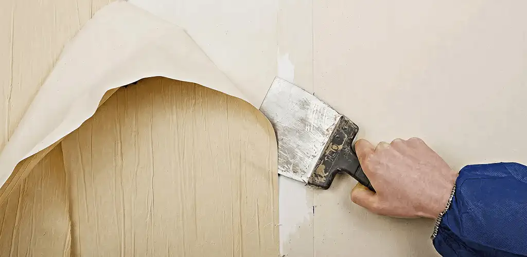 Handyman removing wallpaper with a scraper for wall preparation in Buffalo, NY