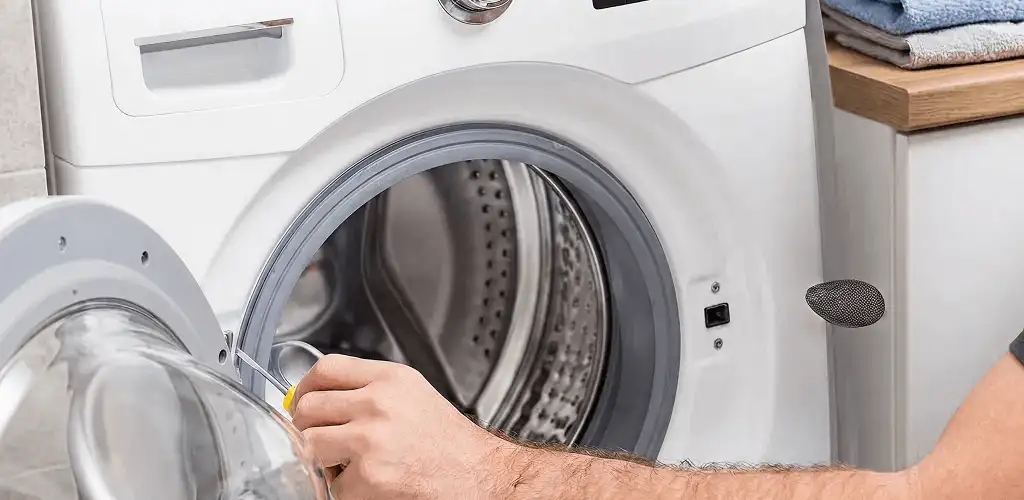Handyman repairing a front-load washing machine and inspecting the drum in Buffalo, NY